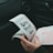 A person is holding and examining what appears to be lottery tickets inside a car. The image is focused on the tickets and the person's hands, with parts of the car interior visible in the background.